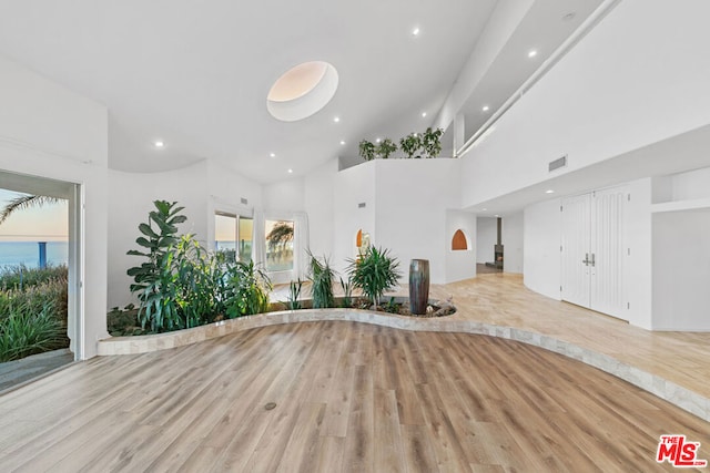 interior space featuring a towering ceiling and light wood-type flooring