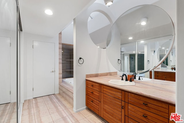 bathroom featuring tile patterned flooring, vanity, and tiled bath