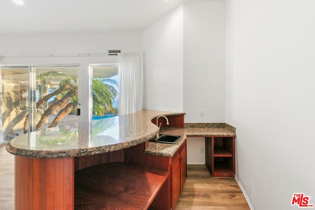 interior space featuring sink, light hardwood / wood-style flooring, and light stone countertops