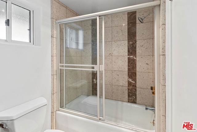 bathroom featuring toilet and combined bath / shower with glass door