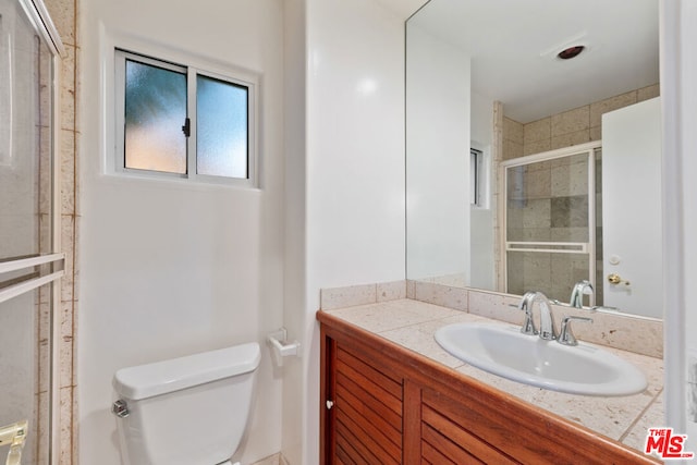 bathroom with vanity, a shower with door, and toilet