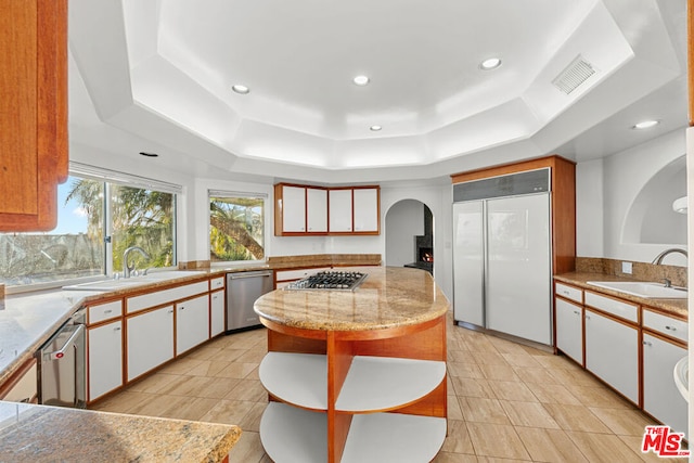 kitchen featuring a raised ceiling, appliances with stainless steel finishes, sink, and white cabinets