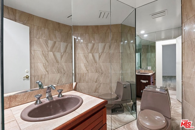 bathroom with tile walls, vanity, and toilet