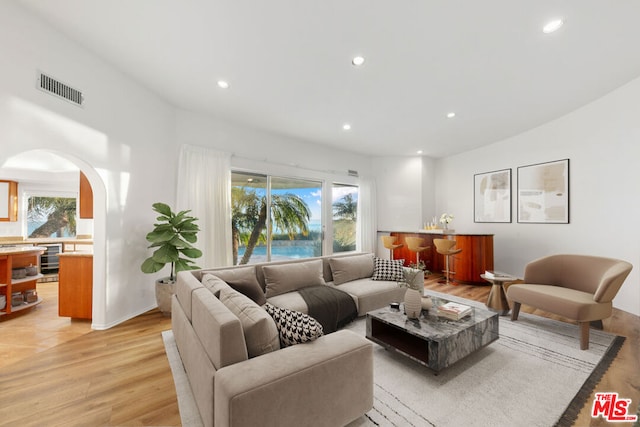 living room featuring wine cooler, a healthy amount of sunlight, and light hardwood / wood-style flooring