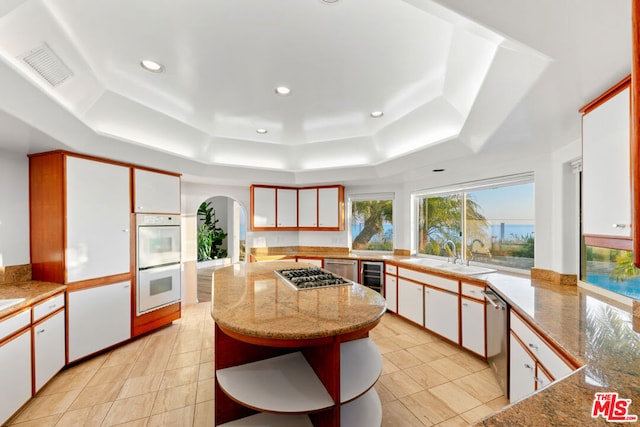 kitchen featuring appliances with stainless steel finishes, sink, wine cooler, white cabinets, and a tray ceiling