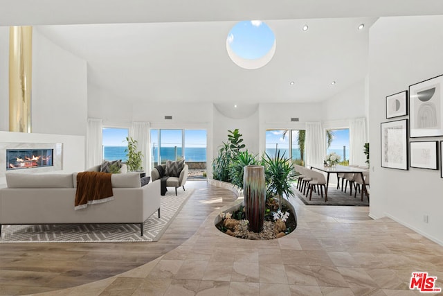 living room with a wealth of natural light, high vaulted ceiling, and a water view