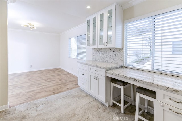 kitchen featuring white cabinetry, light stone countertops, crown molding, and decorative backsplash