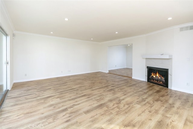 unfurnished living room featuring crown molding, a high end fireplace, and light hardwood / wood-style flooring