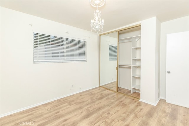 unfurnished bedroom featuring a closet, a chandelier, and light wood-type flooring