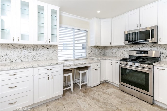 kitchen with stainless steel appliances, tasteful backsplash, light stone countertops, and white cabinets