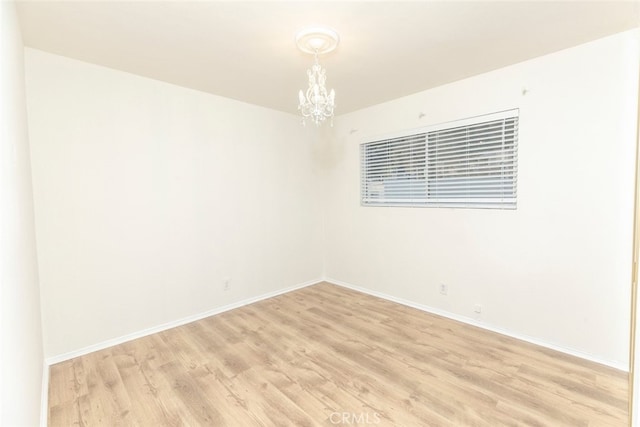 unfurnished room featuring light hardwood / wood-style flooring and a chandelier