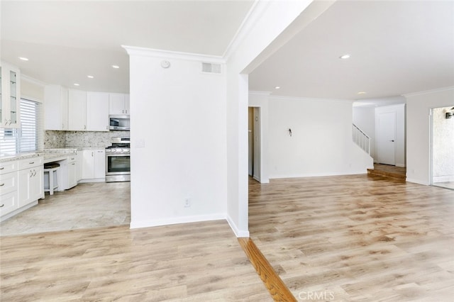 kitchen featuring white cabinetry, decorative backsplash, light hardwood / wood-style flooring, and stainless steel appliances