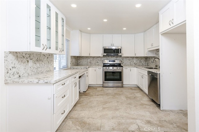 kitchen featuring stainless steel appliances, light stone countertops, and white cabinets