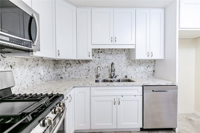 kitchen featuring sink, white cabinets, backsplash, stainless steel appliances, and light stone countertops