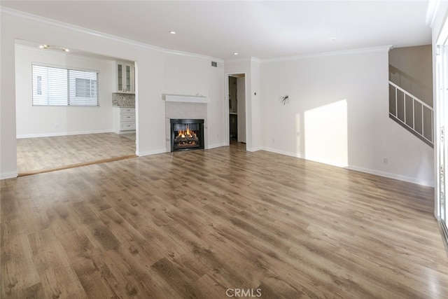 unfurnished living room with wood-type flooring and ornamental molding