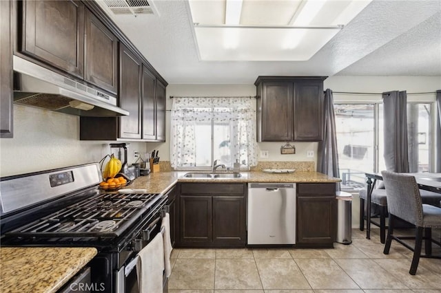 kitchen with stainless steel appliances, light stone countertops, sink, and dark brown cabinetry