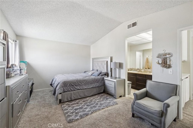 carpeted bedroom with ensuite bath, vaulted ceiling, and a textured ceiling