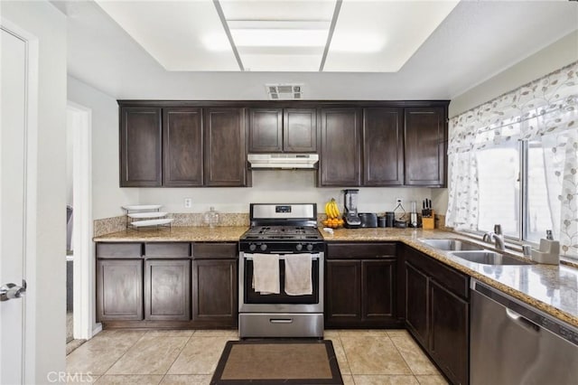 kitchen featuring sink, light tile patterned floors, dark brown cabinetry, stainless steel appliances, and light stone countertops