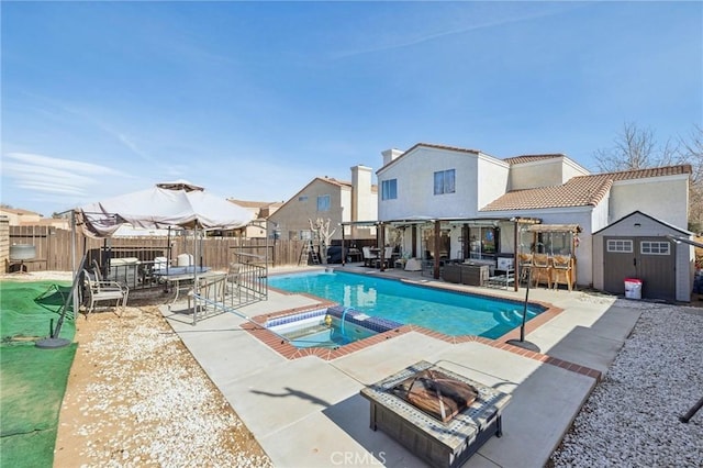 view of swimming pool featuring an in ground hot tub, an outdoor living space with a fire pit, a patio area, and a shed