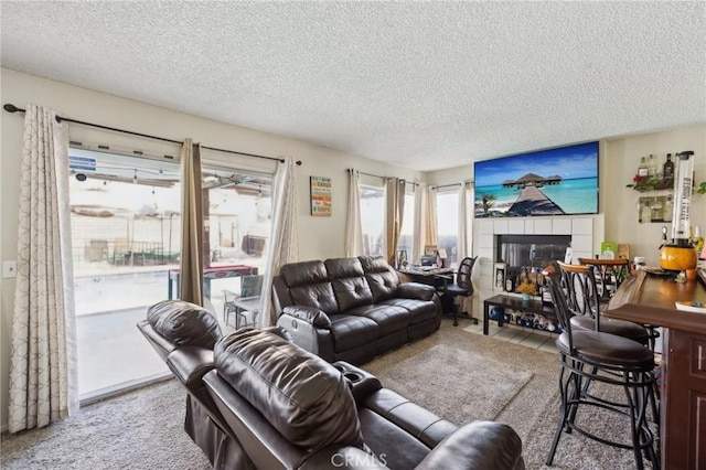 carpeted living room featuring a tiled fireplace and a textured ceiling