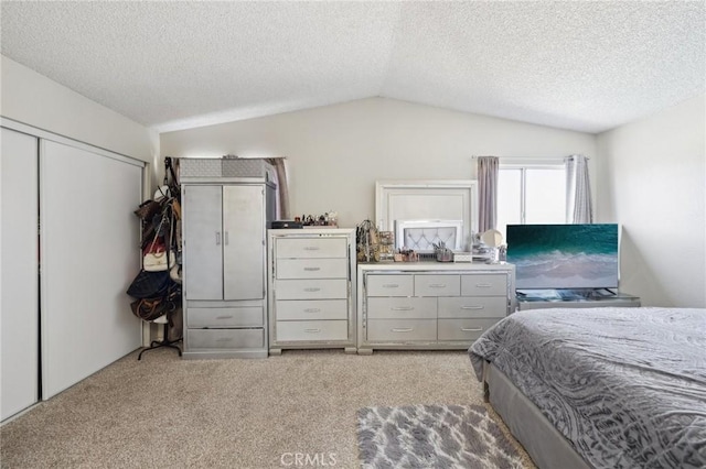 bedroom with vaulted ceiling, light carpet, a textured ceiling, and a closet