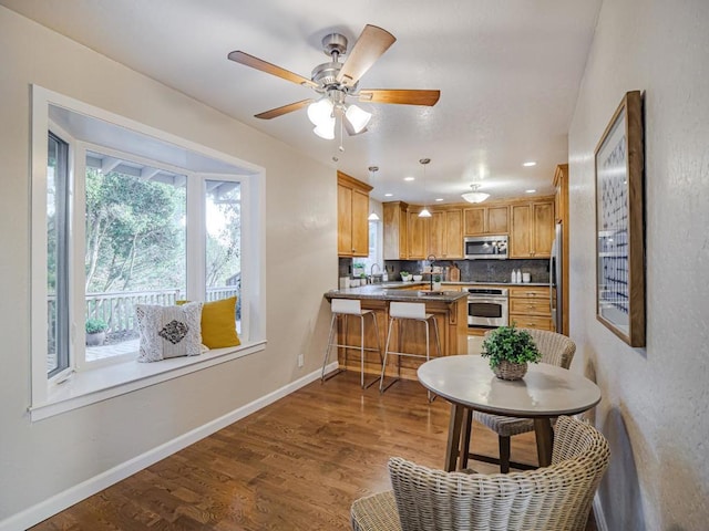 kitchen featuring sink, dark wood-type flooring, a breakfast bar area, stainless steel appliances, and kitchen peninsula