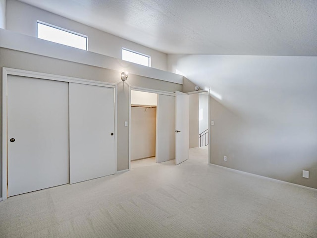 additional living space featuring lofted ceiling, light colored carpet, and a textured ceiling