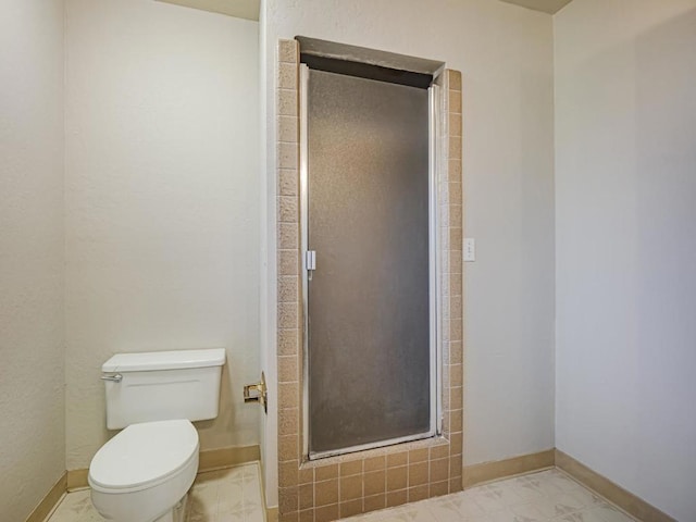 bathroom with a shower with shower door and toilet