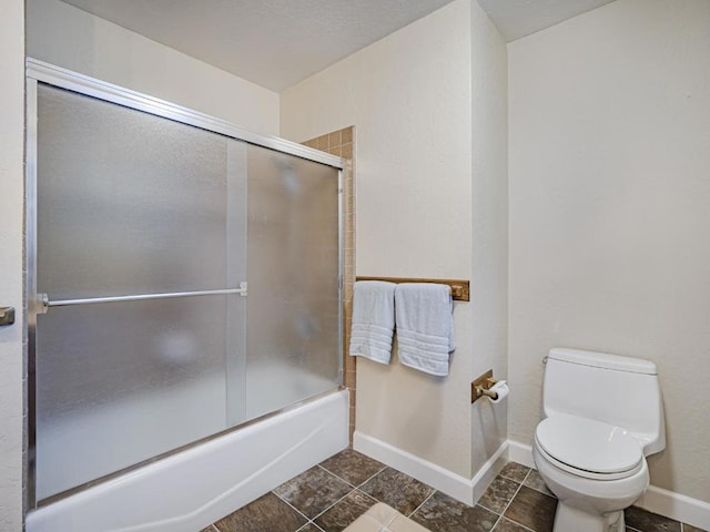 bathroom featuring shower / bath combination with glass door and toilet