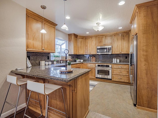 kitchen with stainless steel appliances, pendant lighting, a kitchen breakfast bar, and kitchen peninsula