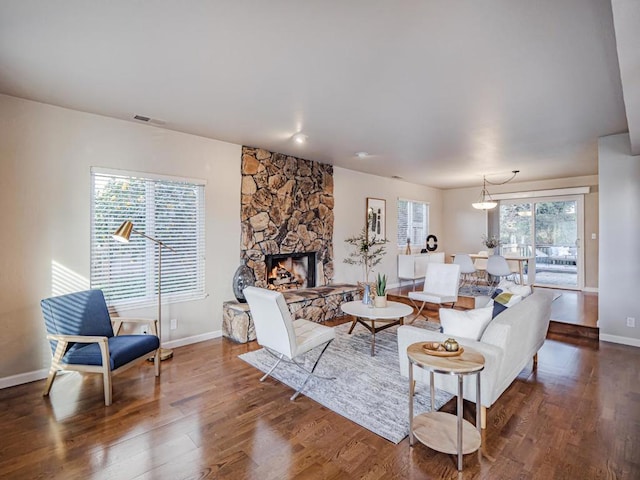 living room featuring a stone fireplace and dark hardwood / wood-style floors