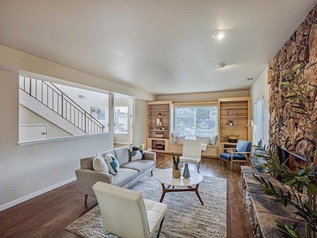 living room featuring dark wood-type flooring and a stone fireplace