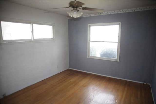 empty room with ceiling fan, a wealth of natural light, and wood-type flooring