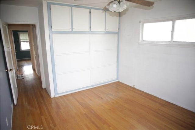 unfurnished bedroom featuring hardwood / wood-style flooring, multiple windows, and a closet