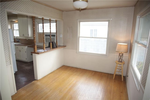 kitchen with white cabinetry, sink, cooling unit, and light wood-type flooring