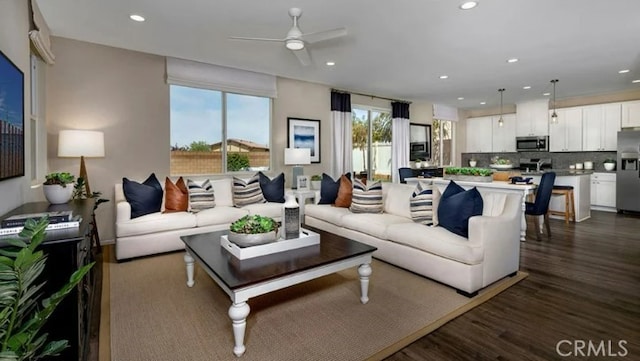 living room featuring dark wood-type flooring and ceiling fan