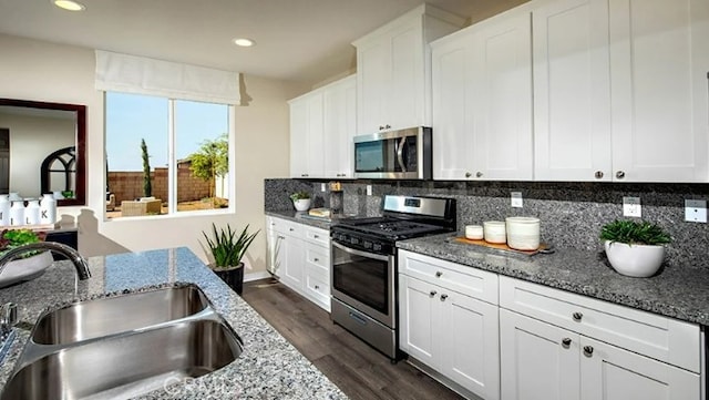 kitchen featuring appliances with stainless steel finishes, stone countertops, tasteful backsplash, sink, and white cabinets