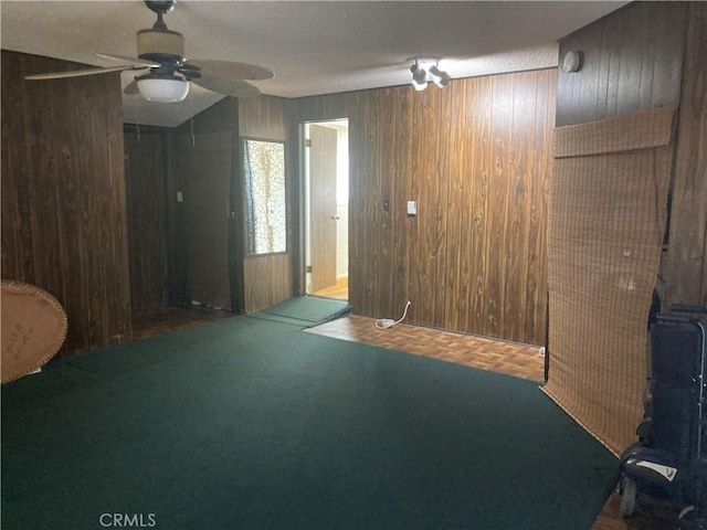 unfurnished room with dark parquet flooring, ceiling fan, and wood walls