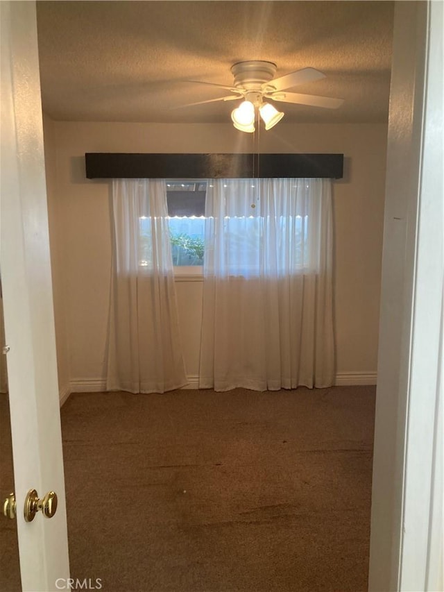 empty room with ceiling fan, carpet flooring, and a textured ceiling