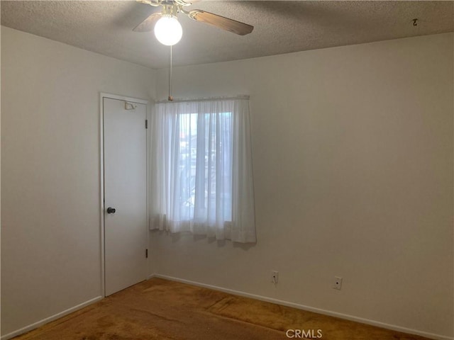 carpeted empty room featuring ceiling fan and a textured ceiling