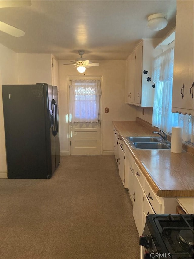 kitchen featuring sink, ceiling fan, white cabinets, black fridge, and range with gas cooktop