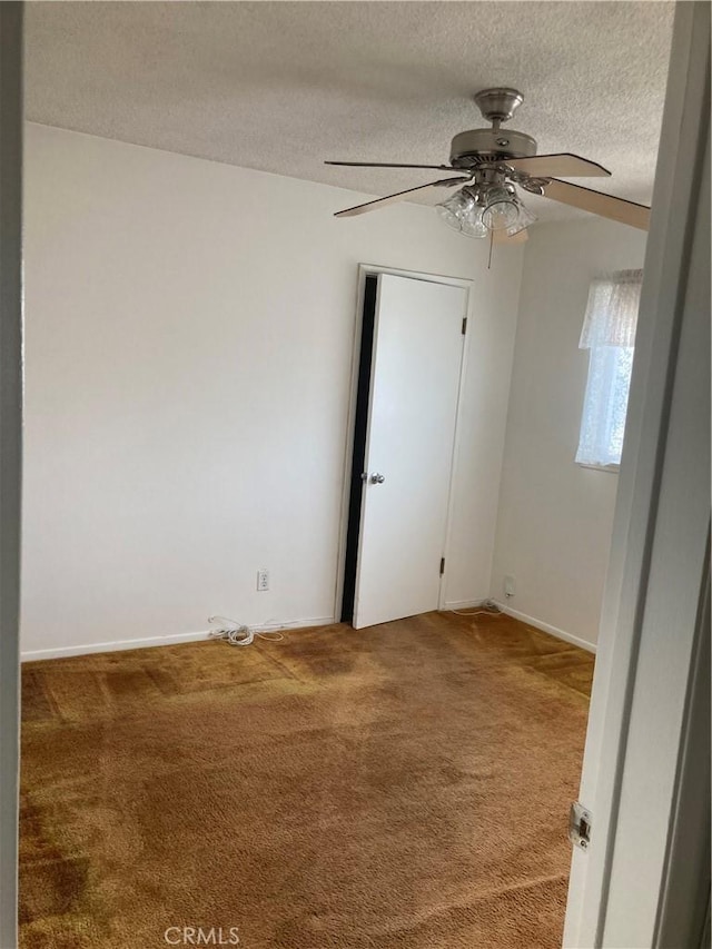 carpeted empty room featuring ceiling fan and a textured ceiling