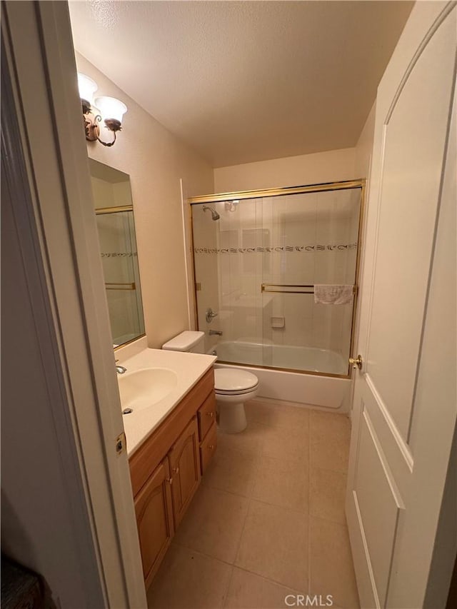 full bathroom featuring tiled shower / bath, tile patterned flooring, vanity, toilet, and a textured ceiling