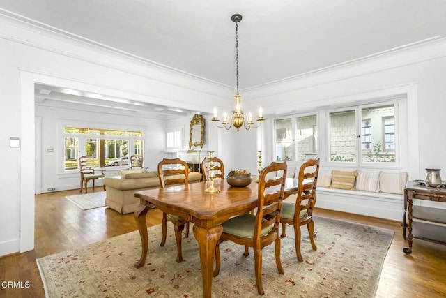 dining space with ornamental molding, hardwood / wood-style floors, and an inviting chandelier