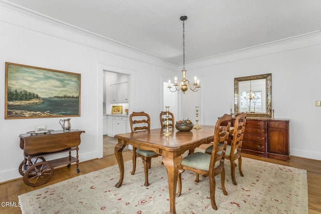 dining space featuring an inviting chandelier, ornamental molding, and light hardwood / wood-style floors