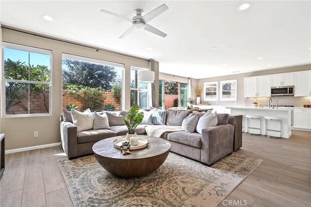 living room with ceiling fan and light hardwood / wood-style flooring