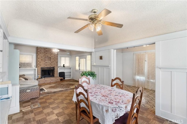 dining area with ceiling fan, dark parquet floors, a fireplace, and a textured ceiling