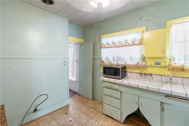 kitchen featuring a drop ceiling, sink, and tile counters