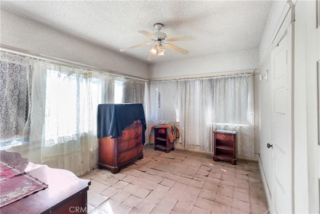 living area with ceiling fan and a textured ceiling