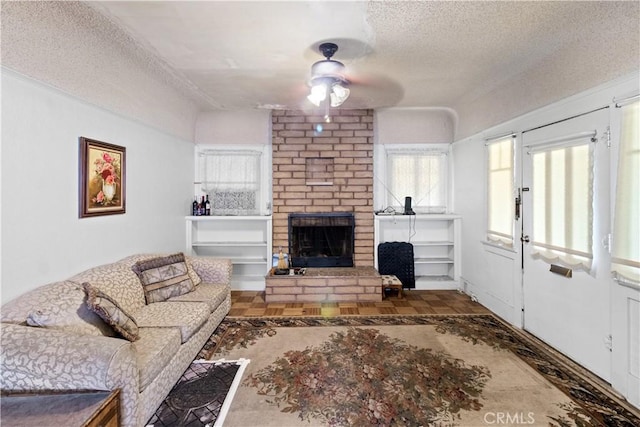 living room featuring parquet floors, ceiling fan, a fireplace, and a textured ceiling